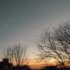 the sky at sunset, with trees and houses in the foreground